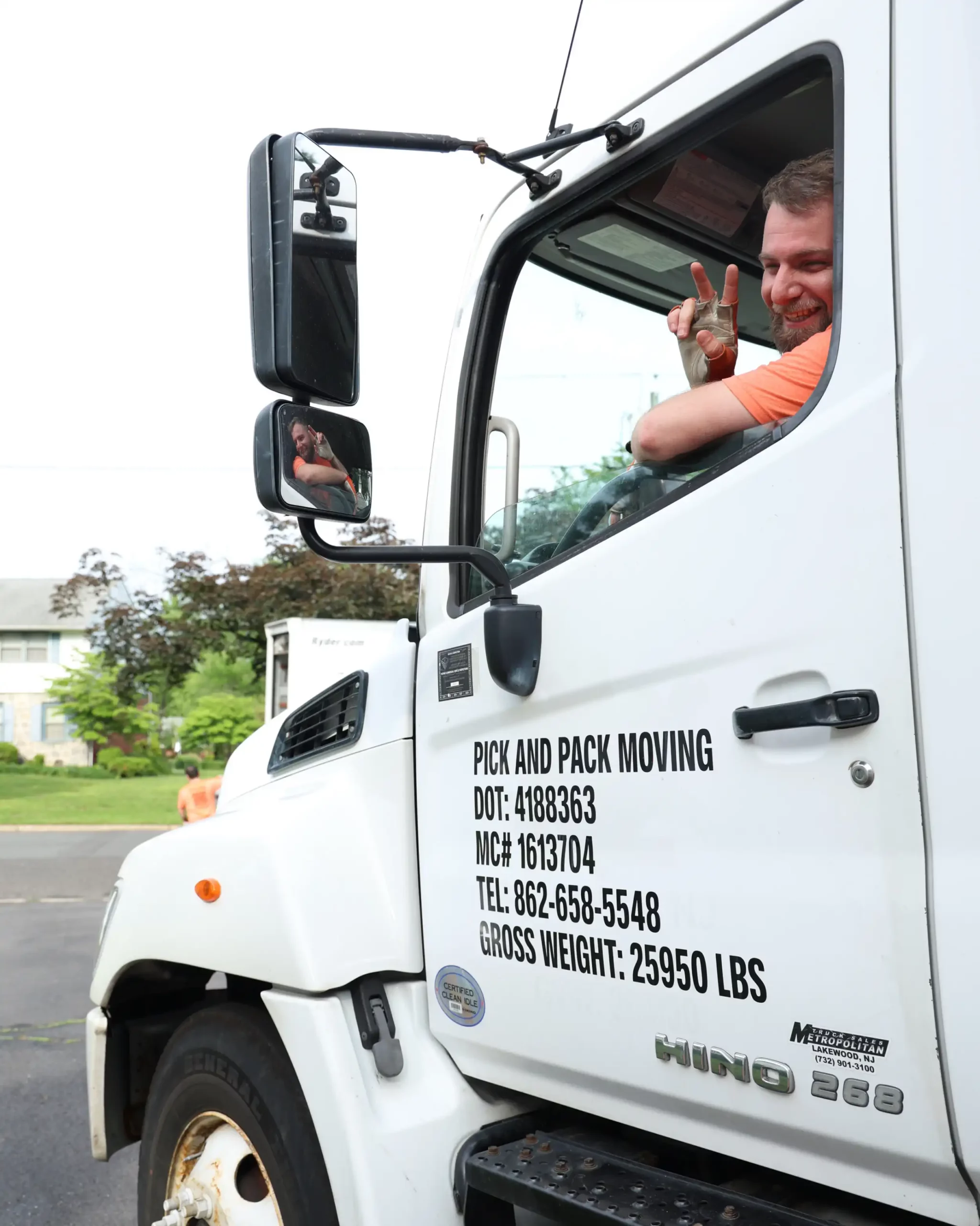 Friendly Pick and Pack truck driver giving a peace sign before starting a long-distance moving journey