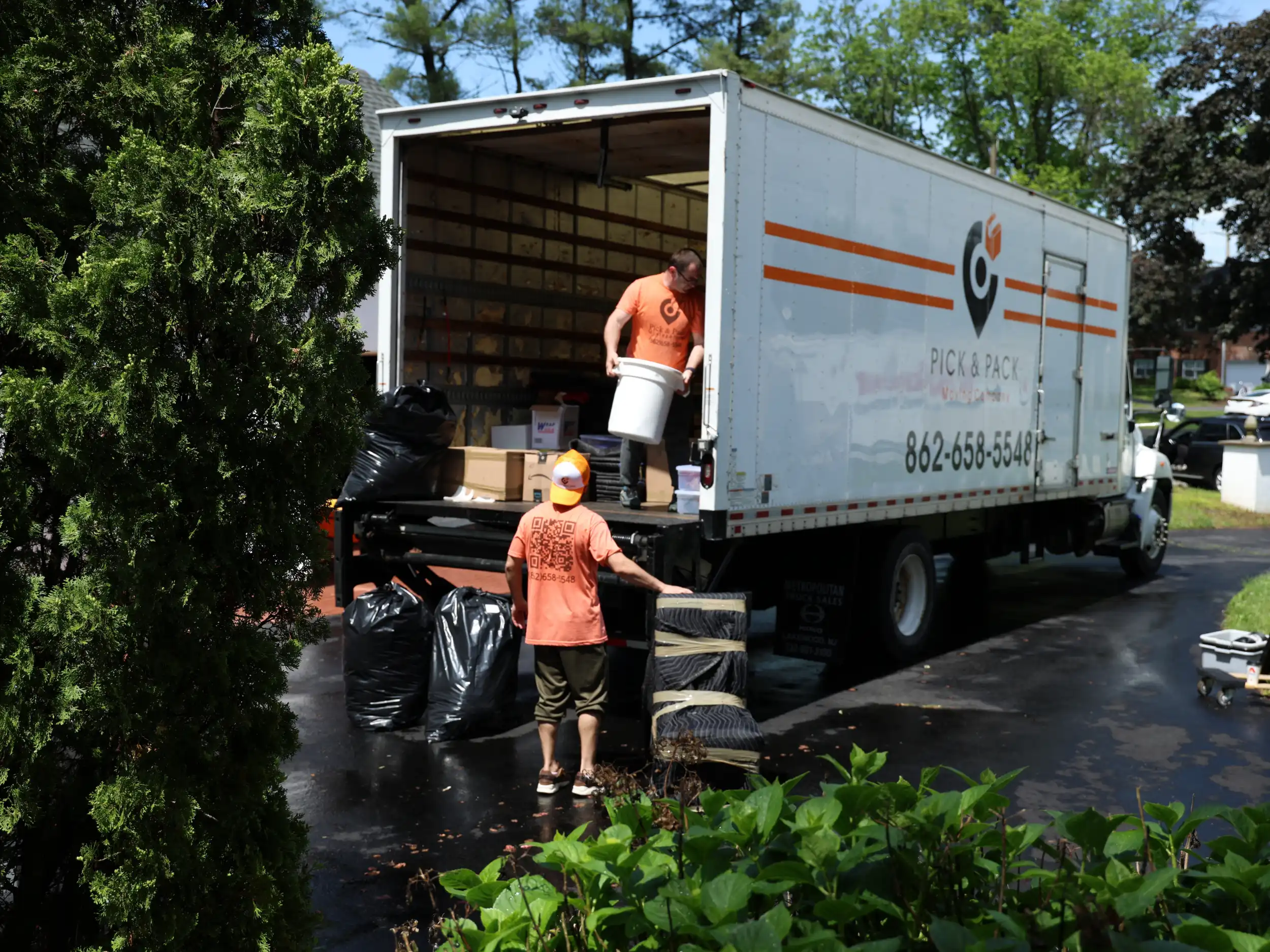 Professional movers loading a Pick and Pack truck for a long-distance move in a residential neighborhood