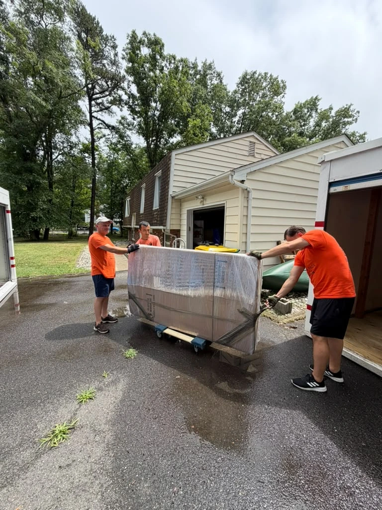 Asbury Park movers wheeling a heavy wrapped item on a dolly during a home move