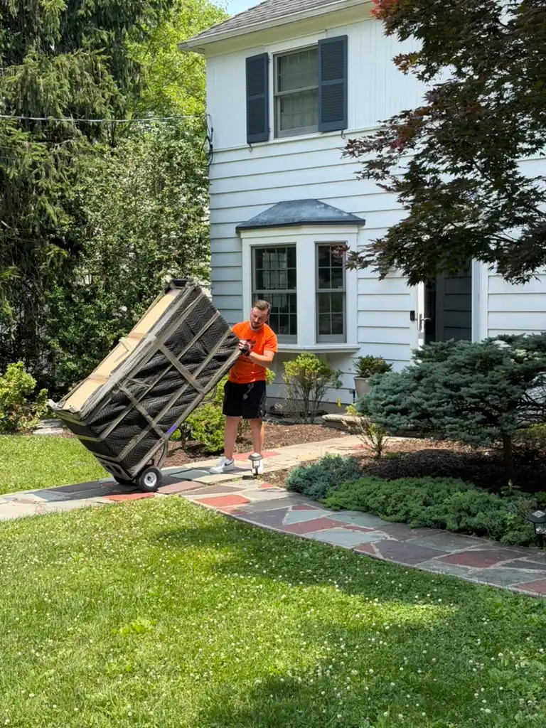 Jersey City mover moving a wrapped item on a hand truck up to a home