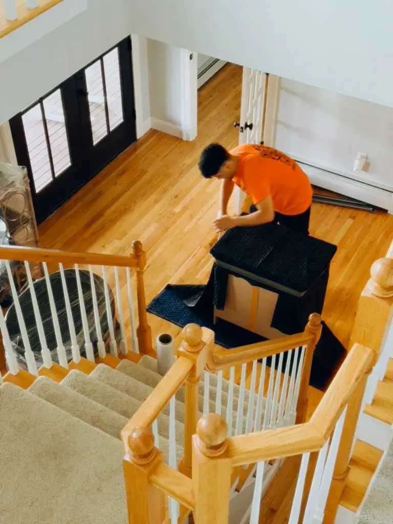 Pick and Pack mover padding and protecting furniture before carrying it downstairs in a New Jersey home
