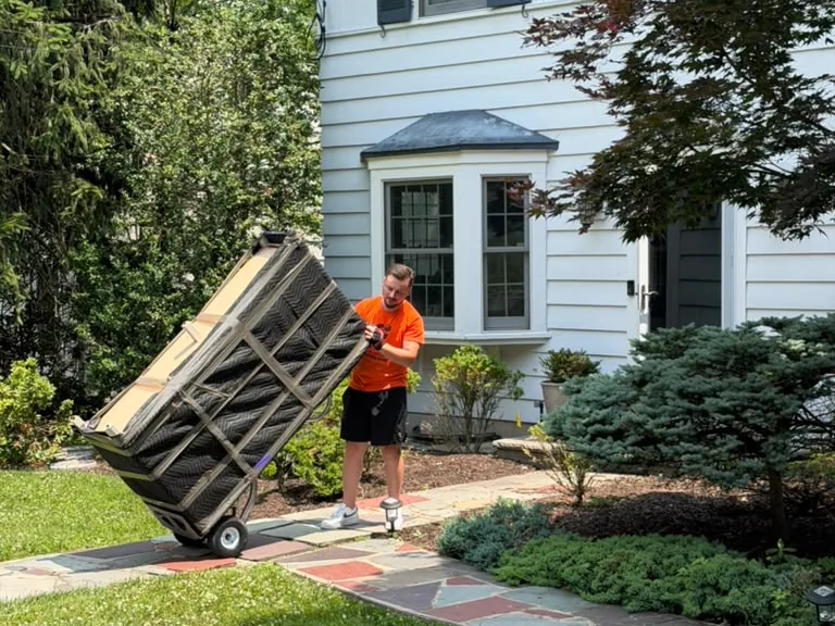 Ho-Ho-Kus movers wheeling a wrapped item up to a home