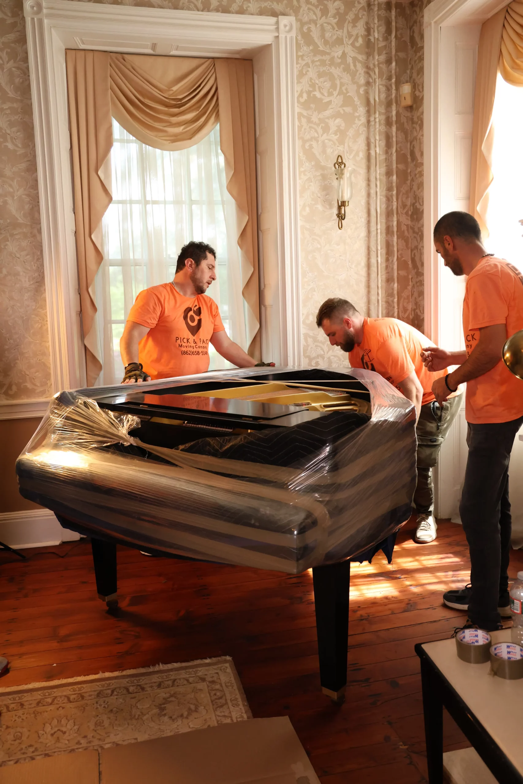 Pick and Pack piano movers carefully wrapping a grand piano for transport