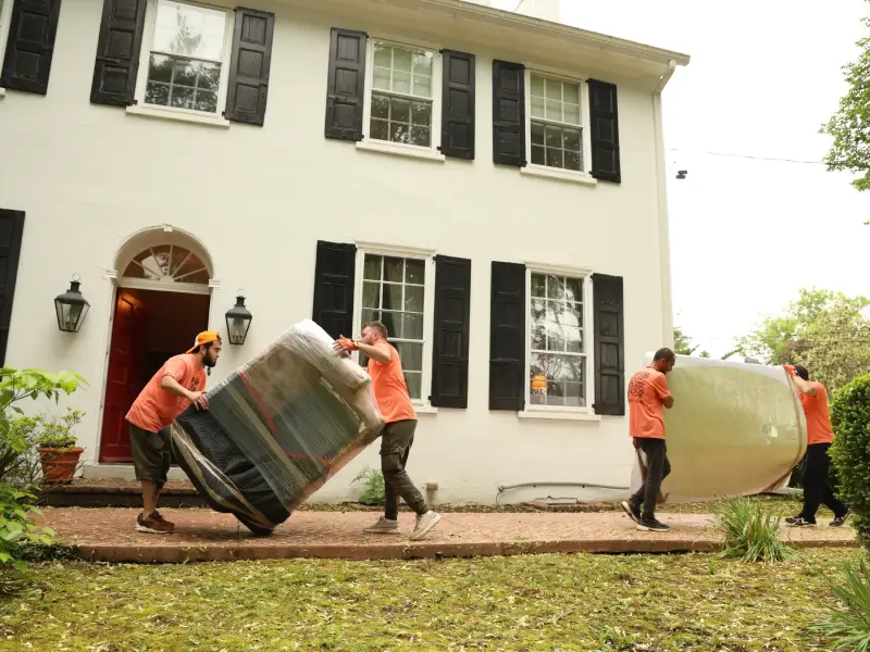 Experienced nj movers carefully moving heavy furniture out of a residential home during a relocation